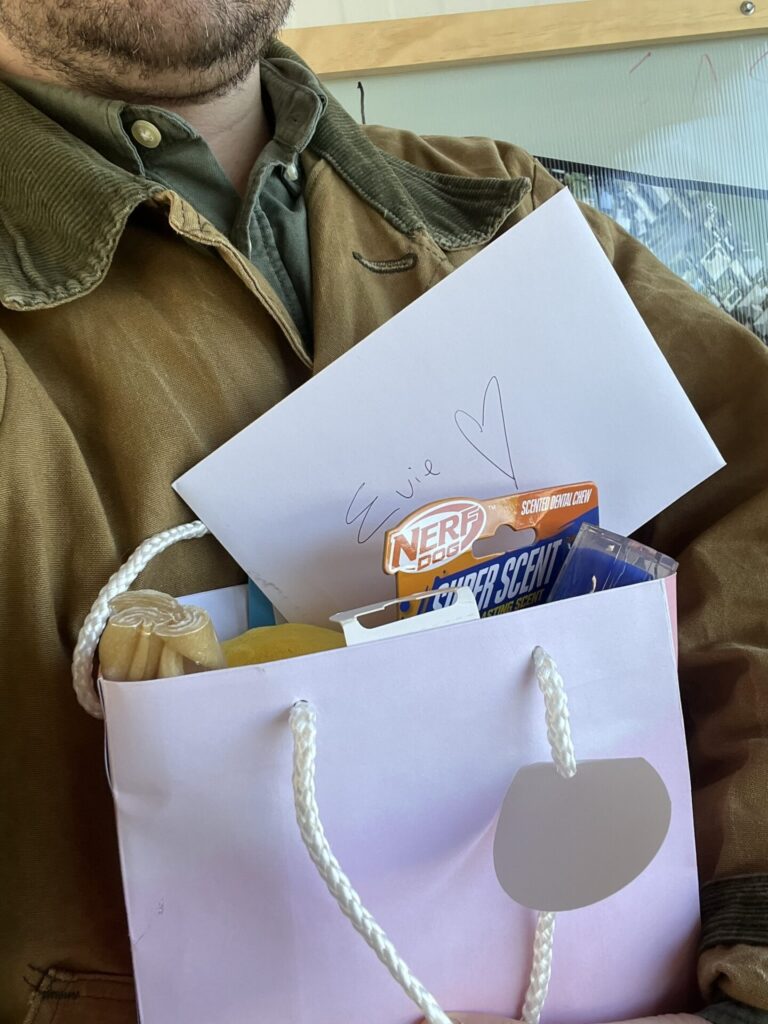 A person holding a goodie bag containing a card and dog treats